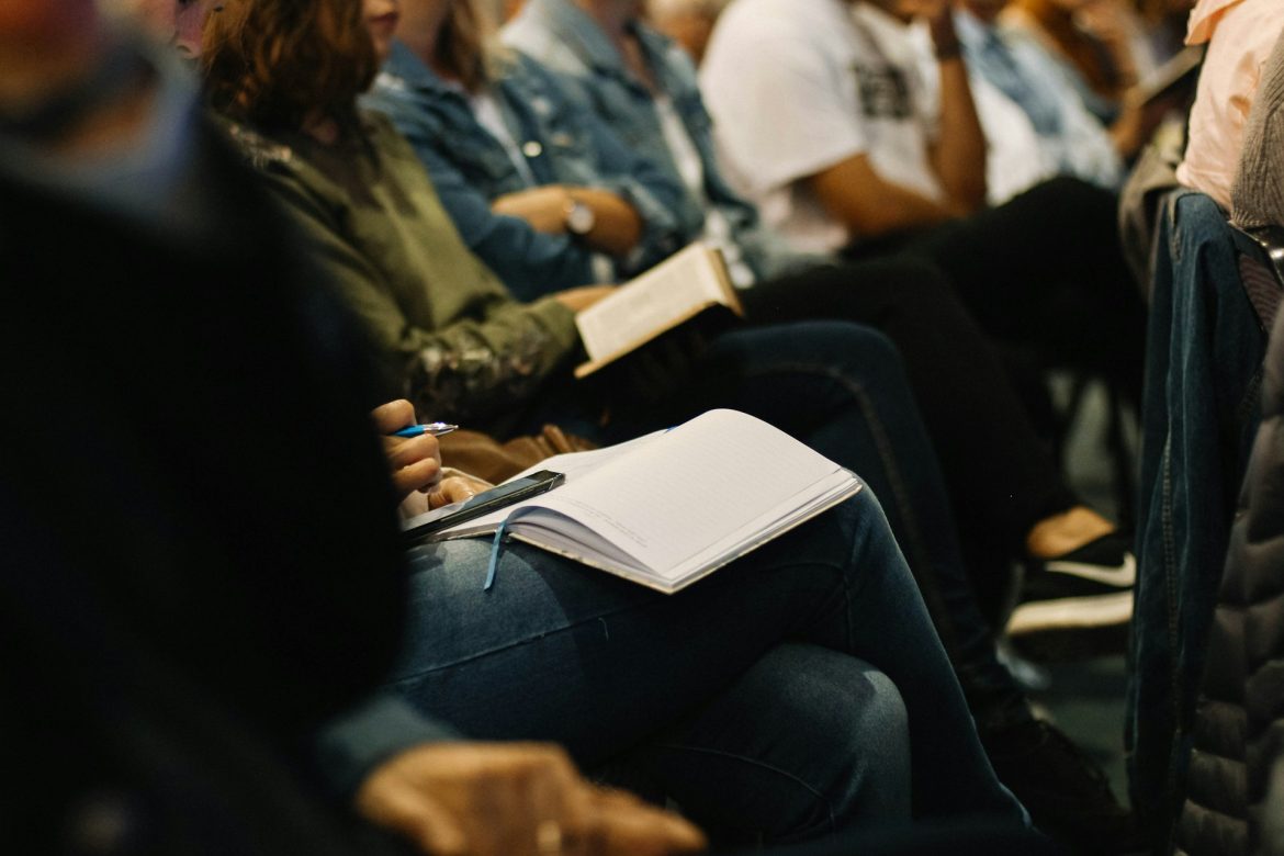 woman taking notes on lap during talk at rmai conference